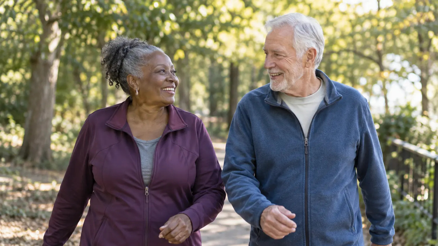 Two older adults enjoying a walk together on a leafy park path.
