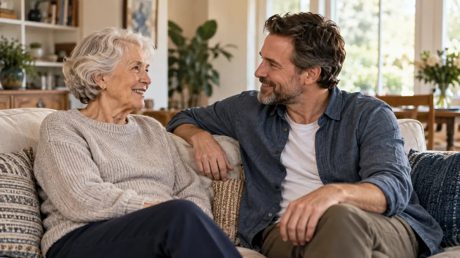 An older woman and her adult son talking together on a sofa.